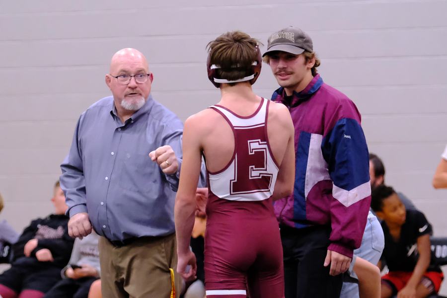 An Edmond wrestler talks with a coach at the edge of the mat
