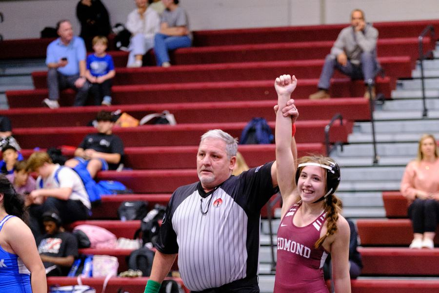 An Edmond wrestler celebrates a win with the referee raising her hand